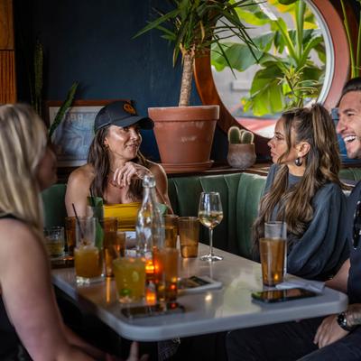 Group of people socializing at a table with drinks in a cozy bar setting.