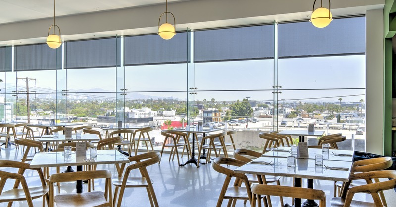A bright, spacious, and cozy dining area with large windows and set dining tables