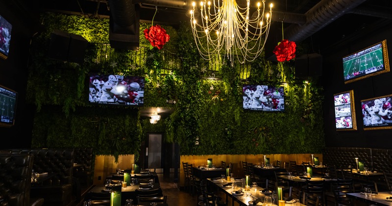 Interior seating area with a green foliage wall and a chandelier
