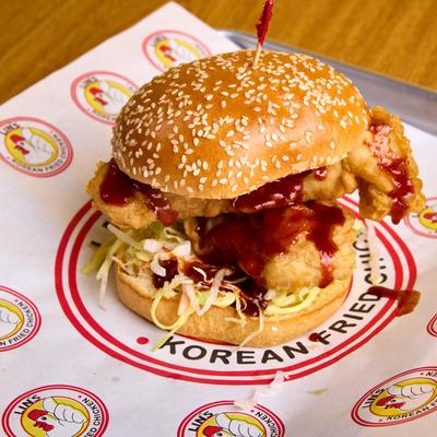 A crispy chicken burger with sauce and coleslaw on a sesame bun.