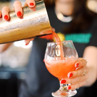 Bartender pouring a cocktail into a glass.