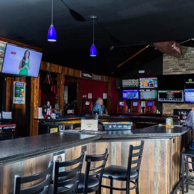 Patrons sit at a bar watching multiple screens displaying races and sports