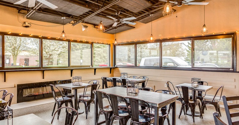 Interior, tables and chairs in dining area with windows behind