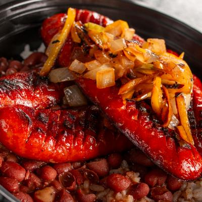 Hot links served over beans, topped with grilled onions, close up.