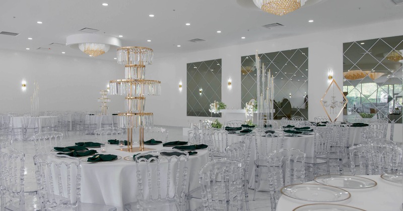 Luxurious banquet hall, white draped tables, clear chairs and tiered gold and glass centerpieces