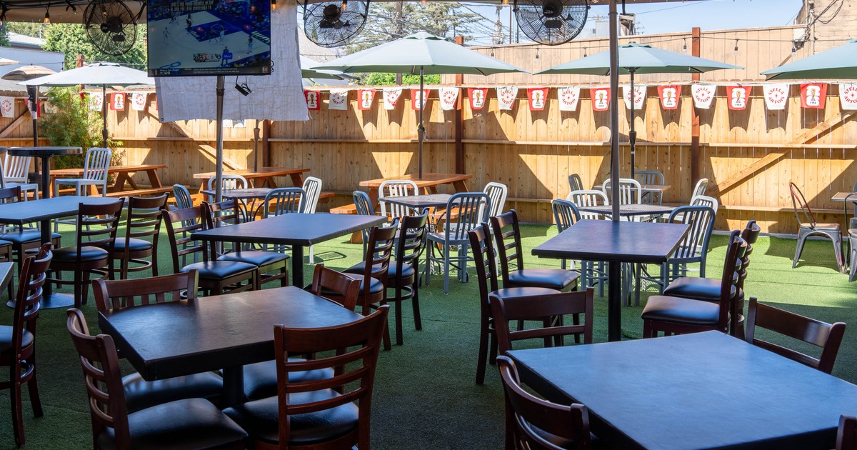 Outdoor dining area with dark wooden tables and chairs