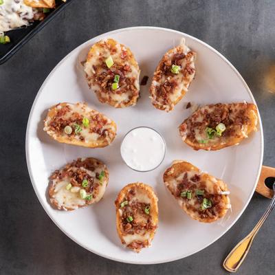 Crispy potato skins, stuffed with cheese, bacon, scallions, and sour cream on the side.