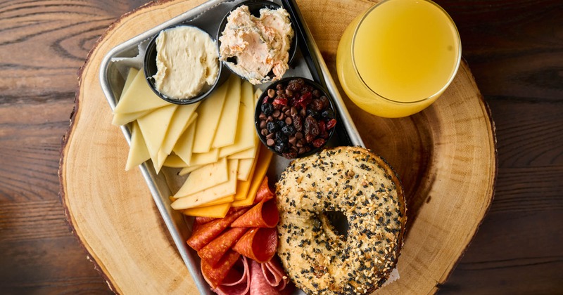 Charcuterie tray with everything bagel and a glass of orange juice