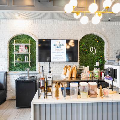 Modern cafe interior with counter service, digital menu board, and decorative greenery.