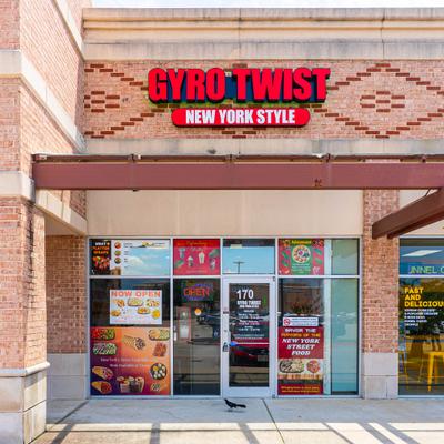 Storefront featuring large glass windows decorated with menu posters and neon signage.
