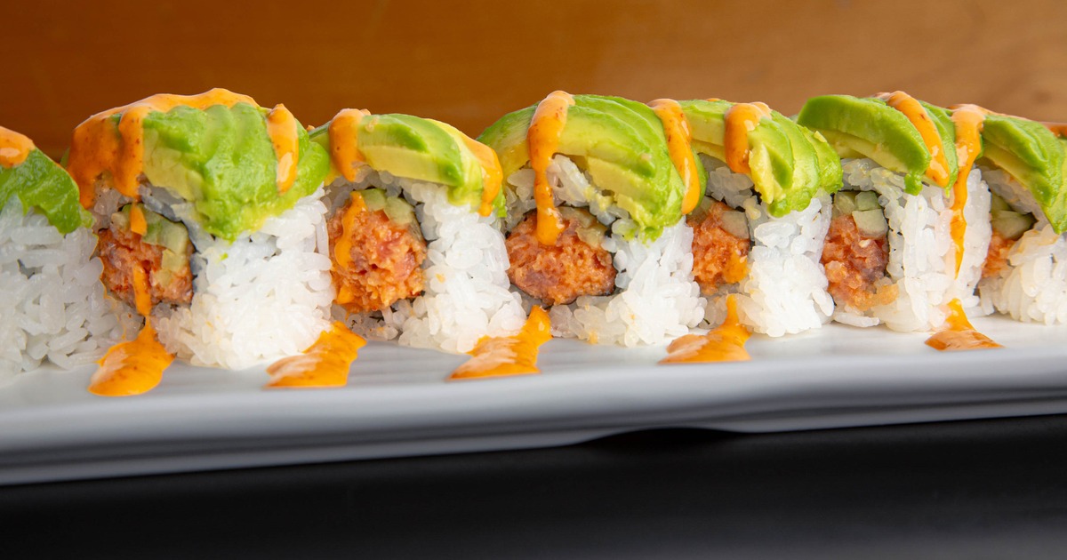Dragon Roll with avocado and a sauce drizzle, close-up view