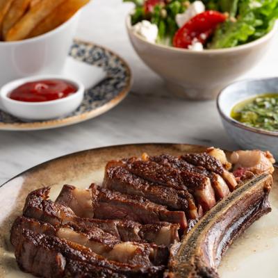 Dry Aged Prime Ribeye served with hand-cut fries, side salad, and Mediterranean Chimichurri