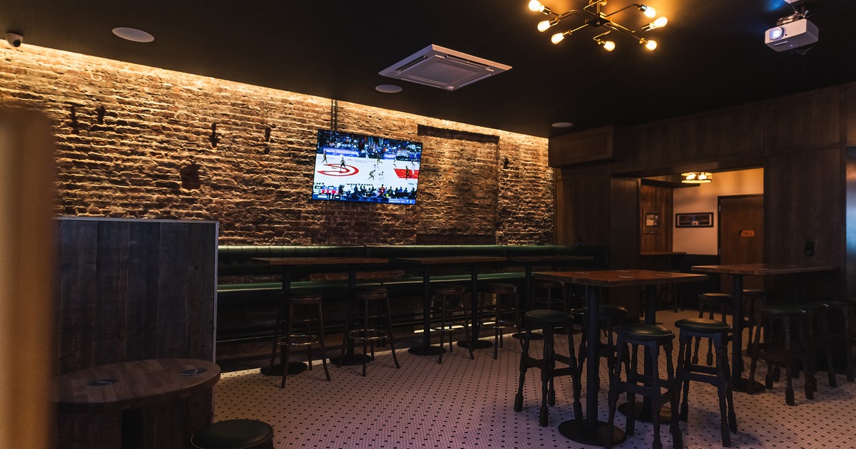 Cozy sports bar seating area with high tables and stools, and booth seating along the wall