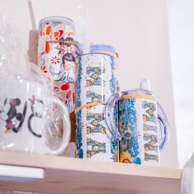 Colorful tumblers and mugs displayed on a wooden shelf.