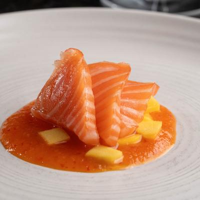 Mango Salmon sashimi served with a sauce.