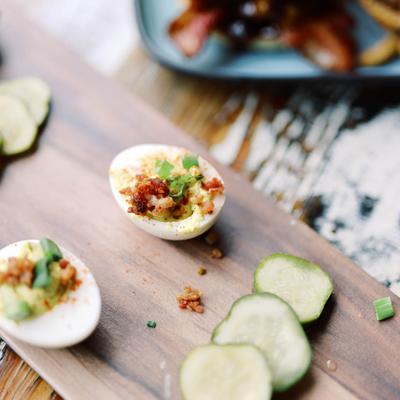 Deviled eggs served with cucumber slices on a wooden board.