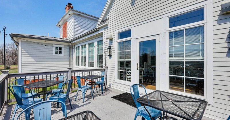 Outdoor patio with light gray siding, black metal tables with blue chairs