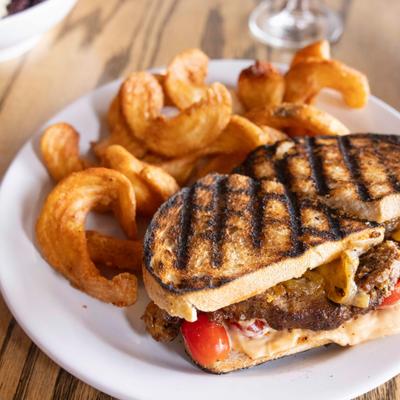 Grilled meatloaf sandwich served with curly fries.