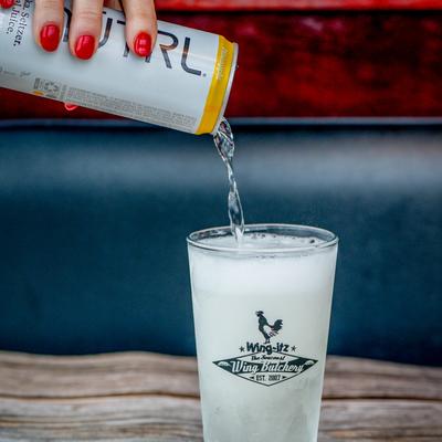 Seltzer being poured into a glass on a rustic wooden table.