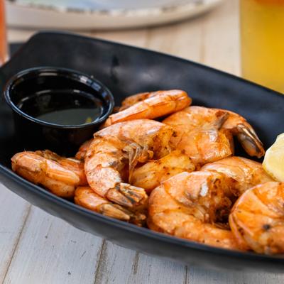 A plate of peel-and-eat shrimp sits beside a cold glass of beer.