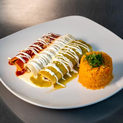 Enchiladas covered in red sauce, cheese sauce, and green sauce, served with rice.