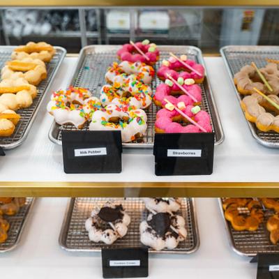 Mochi donuts in a bakery display case showcasing colorful frosting and various toppings.