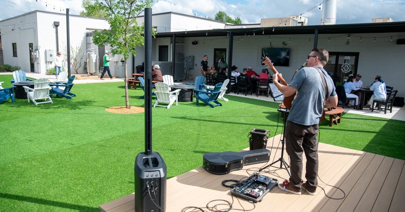 Exterior, mini stage on the lawn, performer on guitar, guests