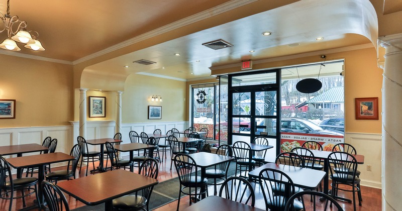 Interior with tables, chairs, artwork and windows showing a street view.