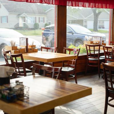 Bright dining room with wooden tables, tiled floors, and large windows.