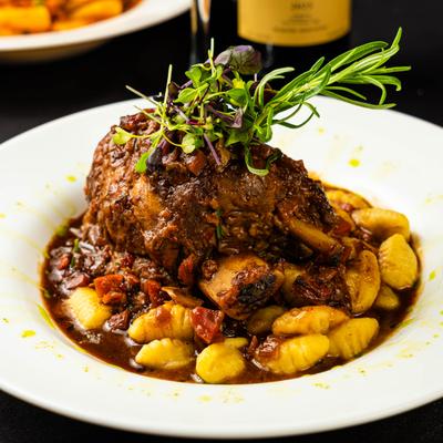 Tender osso bucco with gnocchi and herb garnish.