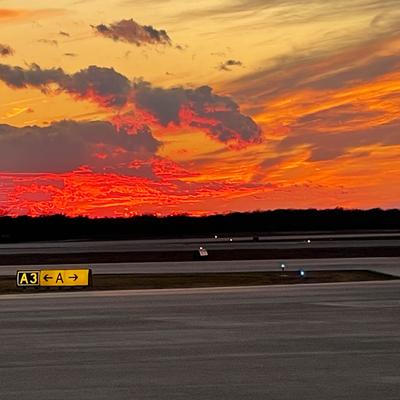 Runway with vibrant hues of orange and purple painting the sky.