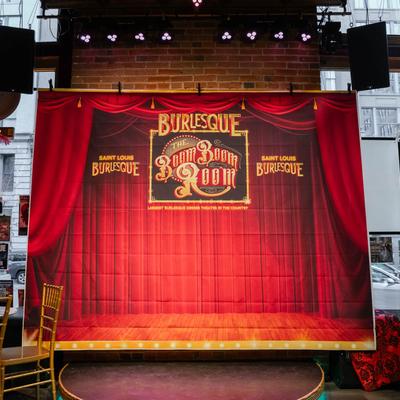 A large poster of a stage with red curtain mounted on a wall inside.