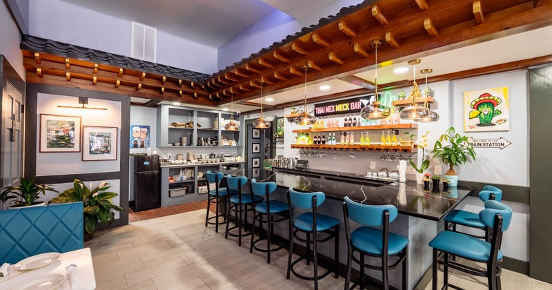 A modern bar area with blue stools, a black counter, and a wooden roof structure