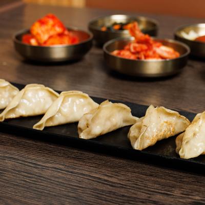 Seoul Haus Dumpling served on black rectangular plate beside side dishes.