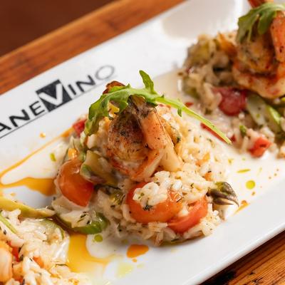Seafood risotto with shrimp and vegetables on a branded plate.