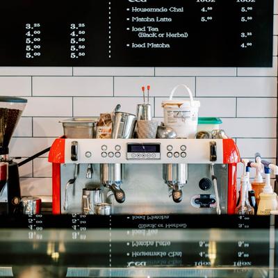 Espresso machine with coffee tools and a coffee menu board above.