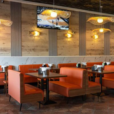 Interior featuring orange booths, wooden accents, and a TV showing a basketball game.