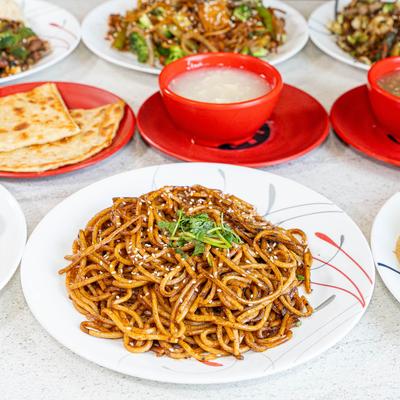 Assorted dishes including stir fried noodles, soups, and bread.