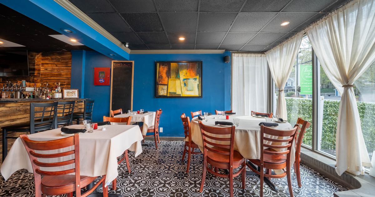 Interior - wooden tables, patterned floor tiles, blue walls and large windows with white curtains