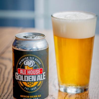 Canned beer next to a glass of frothy beer on a wooden table.