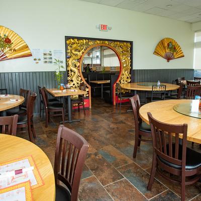 Interior with round wooden tables, decorative fans on the walls, and an ornate archway.