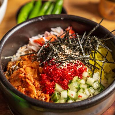 Hot stone rice bowl with fish roe, vegetables, and dried seaweed.