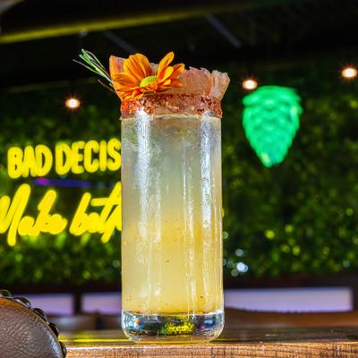 Cocktail served in a colins glas, garnished with grapefriut wedge and a flower.