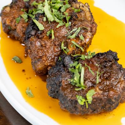 Oxtail served in a sauce and garnished with fresh herbs.