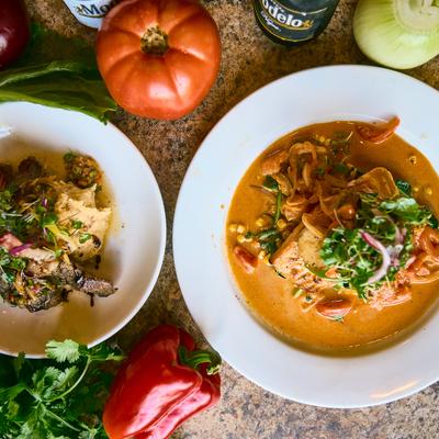 Seafood dish plate and lamb chop plate on a table with fresh vegetables, top view.