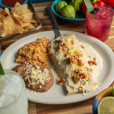 Smothered Burrito topped with a cheese sauce and pico de gallo, served with rice and beans.
