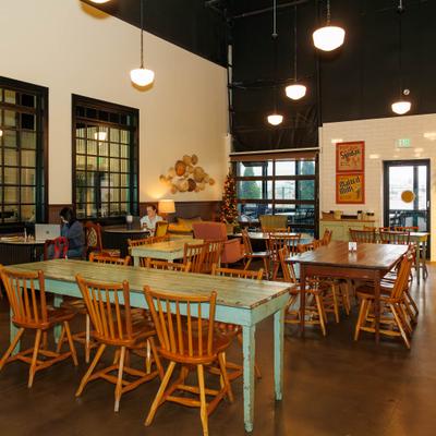 Dining area with wooden tables, pendant lighting, and a Christmas tree in the background.
