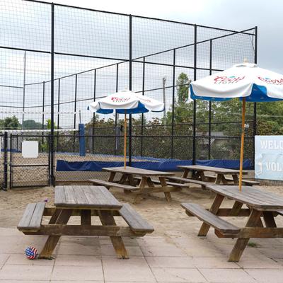 Outdoor seating area, conjoined tables and benches with parasols.