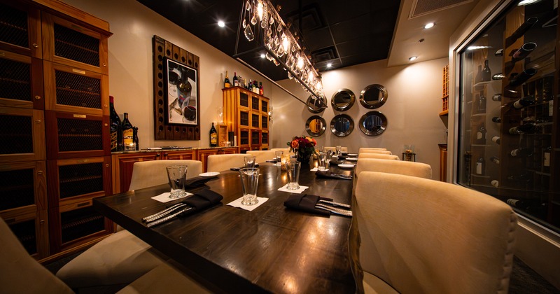 Modern and intimate wine room with a long wooden table set for twelve guests