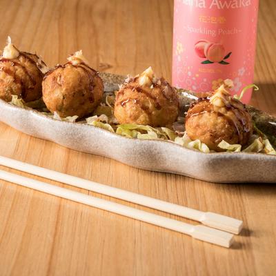 Japanese octopus balls and a bottle sparkling peach drink on the table.